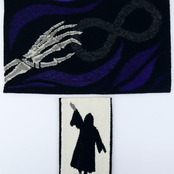 original artwork in hand woven tapestry of a skeleton hand holding an infinity symbol, with a cloaked figure underneath in a separate small tapestry